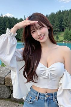 Woman in a white off-shoulder top and jeans smiling outdoors by a lake