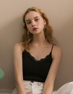Woman with long wavy hair wearing a black lace-trim camisole and hoop earrings