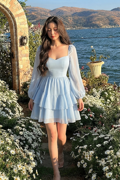 Woman in a light blue dress walking through a field of daisy flowers by a lake