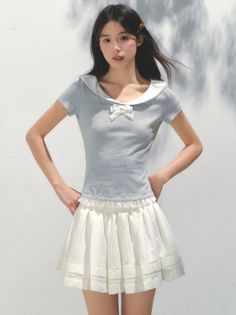Woman with long black hair wearing a sailor collar shirt and white skirt