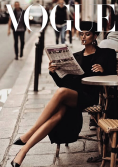 Woman in a black dress reading a newspaper at a street cafe