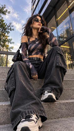 Woman in sunglasses and a crop top sitting on outdoor stairs