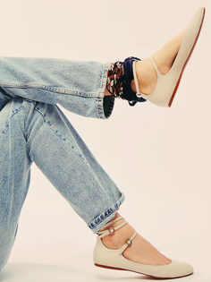 Person wearing light wash jeans and ballet flats with ankle straps