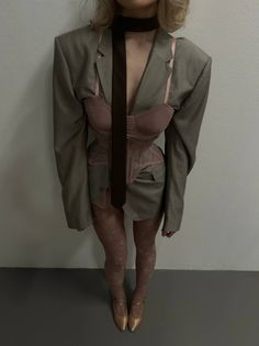 Woman in an oversized blazer, pink corset, and patterned tights