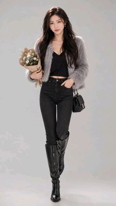 Woman in a gray fur jacket, black top, and jeans holding a bouquet