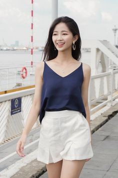 Woman in a navy camisole and white shorts smiling outdoors