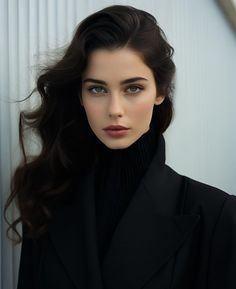 Woman with long dark hair wearing a black turtleneck and blazer
