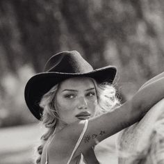 Woman with blonde hair and a cowboy hat in a black and white outdoor portrait