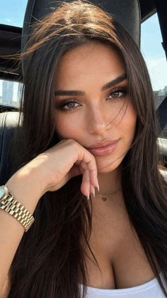 Woman with long dark hair and a gold watch, showing cleavage
