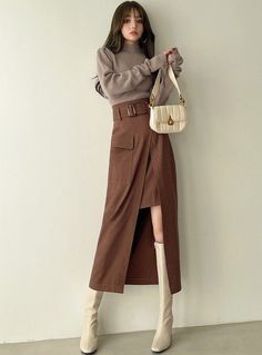 Woman in a brown turtleneck sweater and skirt with white boots and handbag