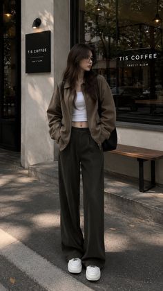 Woman in a crop top and wide leg pants standing outside a coffee shop