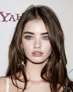 Close-up portrait of a woman with long brown hair and blue eyes