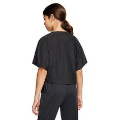 Young person in a black t-shirt and black pants with a ponytail, seen from behind