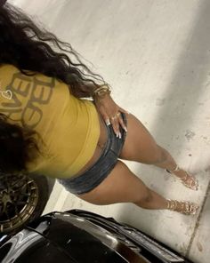Woman in a yellow top and denim shorts with long hair and high heels