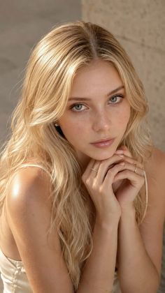 Blonde woman with long hair and freckles, wearing jewelry, in a soft lighting portrait