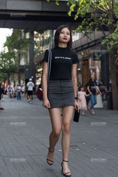 Woman in a black crop top and denim skirt walking on a street