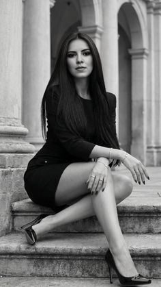 Woman in a black dress and high heels sitting on stone steps