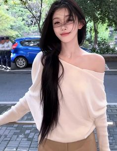 Woman with long black hair wearing an off-shoulder top on a street