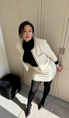 Woman in a tweed jacket and mini skirt with black tights and high heels indoors