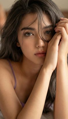 Woman with long dark hair and a purple top looking directly at the viewer