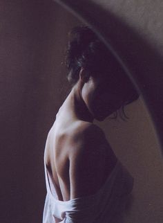 Woman with exposed back in a dark, backlit indoor setting