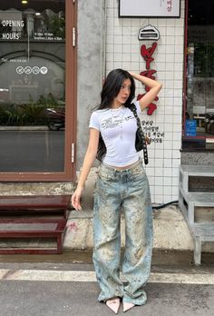 Woman with long black hair wearing a white crop top and baggy jeans outdoors