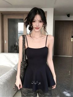 Woman with short black hair wearing a black dress and hoop earrings indoors