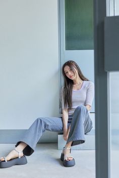Woman with long hair and braids wearing wide leg pants and platform sandals indoors