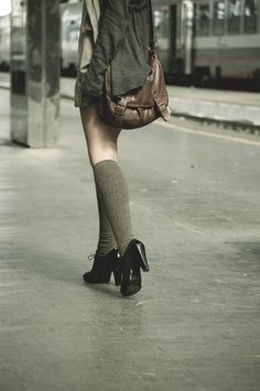 Person with a brown bag and knee-high socks walking at a train station