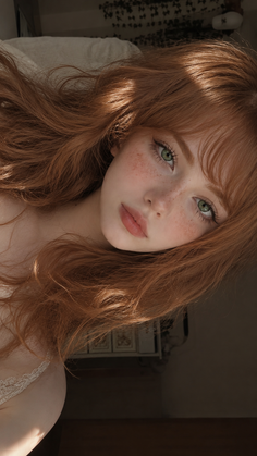Close-up portrait of a woman with long red hair, green eyes, and freckles