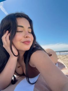 Woman with long dark hair lying on a towel at the beach