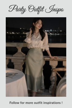 Woman in a white blouse and satin skirt on a balcony at night