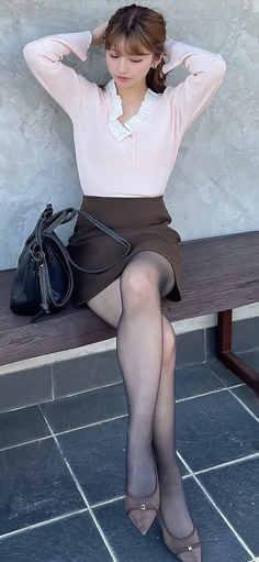 Woman with brown hair wearing a pink top and mini skirt, sitting outdoors