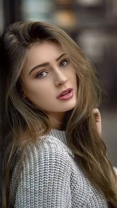 Woman with long hair and blue eyes wearing a gray sweater