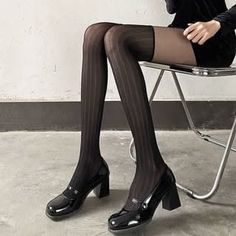 Person in black stockings and high heels sitting on a chair indoors