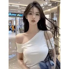 Woman with long dark hair wearing a white off-shoulder top indoors
