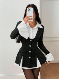 Woman in a black blazer and white shirt taking a mirror selfie