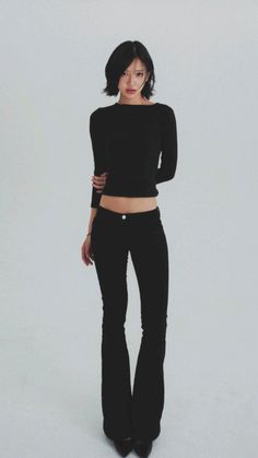 Woman with short black hair in a black top and pants, exposing her midriff