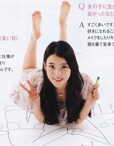 Woman in a floral dress lying down, making a peace sign and drawing