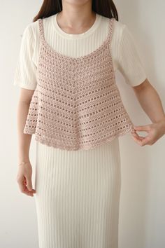 Woman wearing a light pink crochet top over a white ribbed dress