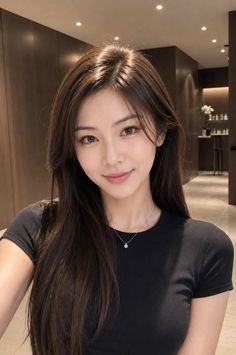 Woman with long dark hair wearing a black t-shirt and silver necklace indoors