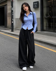Woman with long hair wearing a striped shirt and wide leg pants on a street