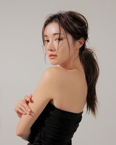 Woman with a ponytail wearing a strapless top, looking over her shoulder