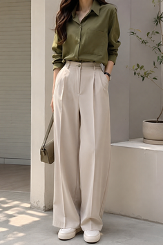 Woman in a green shirt and wide leg pants with a shoulder bag outdoors