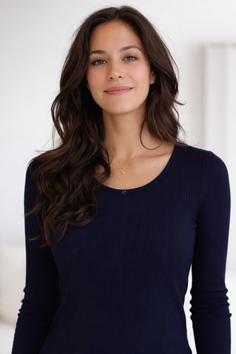Woman with long dark hair wearing a navy blue long-sleeved shirt and a gold necklace