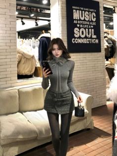 Woman in a gray top and mini skirt holding a phone in a shopping mall