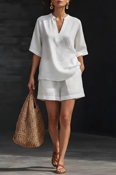 Woman in a white linen shorts and blouse set, holding a straw bag