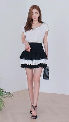 Woman in a white top and black ruffle skirt with a handbag