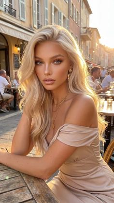 Blonde woman in an off-shoulder dress at an outdoor cafe during golden hour