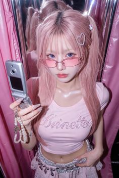 Woman with pink hair and glasses holding a flip phone in a pink setting